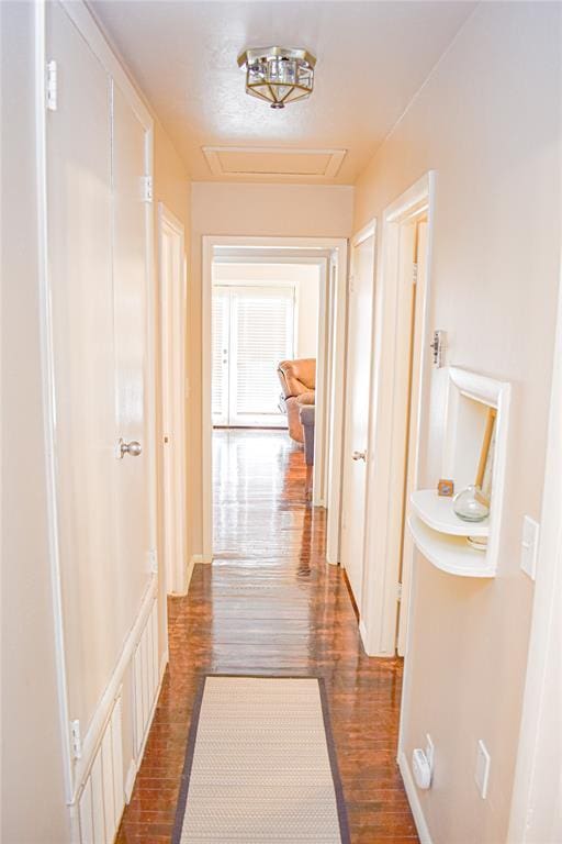 hall featuring attic access and dark wood-style flooring