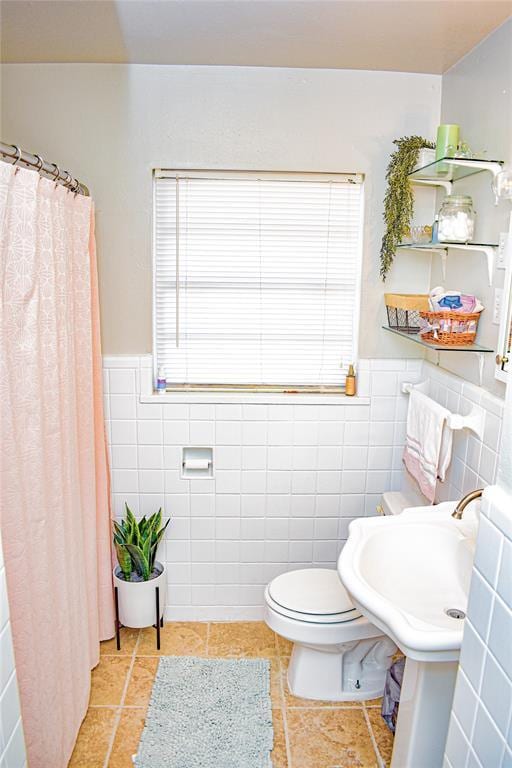 full bath featuring tile patterned floors, toilet, a wealth of natural light, and wainscoting