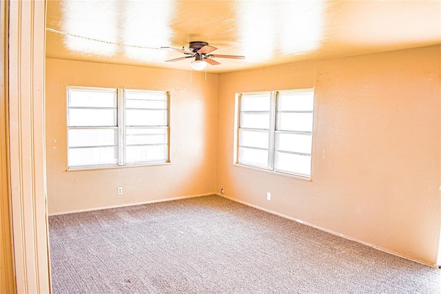 carpeted spare room featuring a ceiling fan and a wealth of natural light