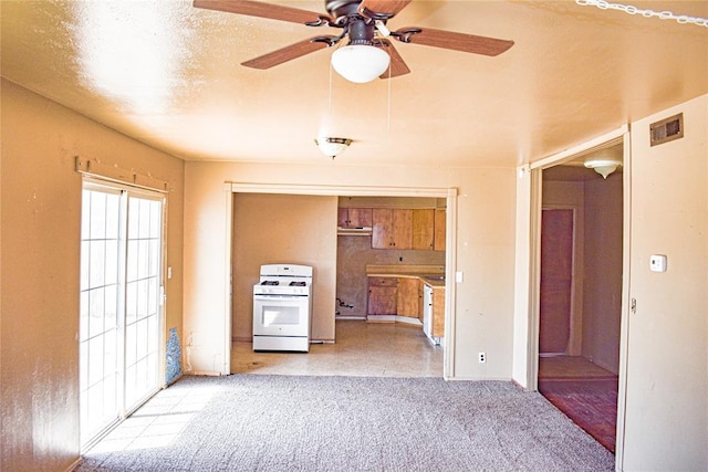 kitchen featuring visible vents, white range with gas stovetop, light carpet, a textured ceiling, and a ceiling fan