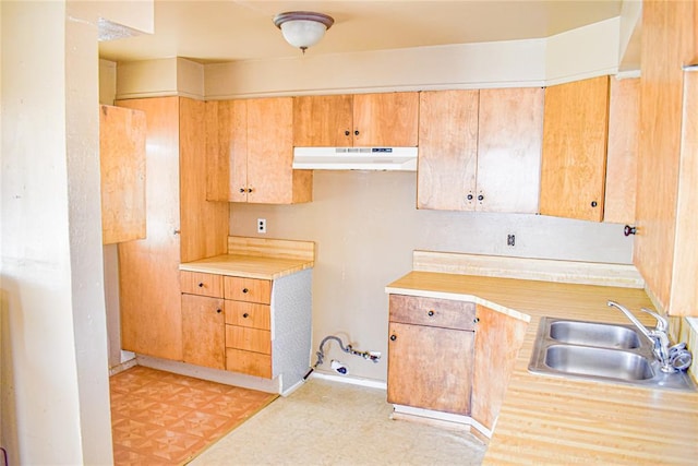 kitchen featuring under cabinet range hood, light floors, light countertops, and a sink