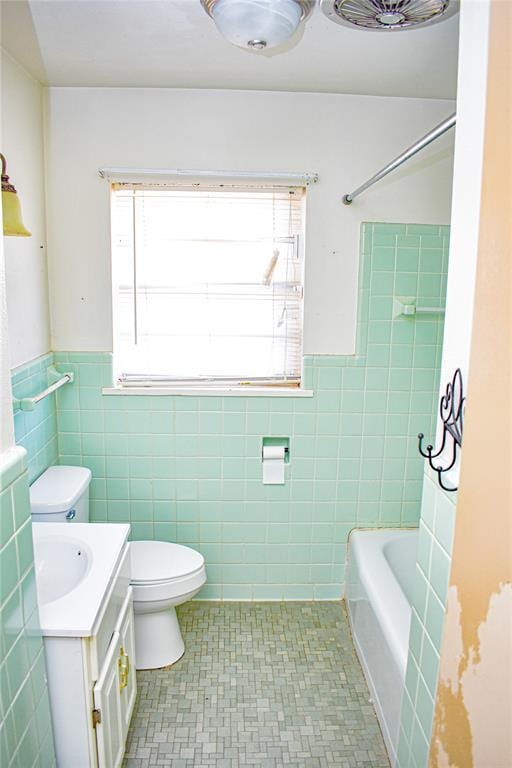 bathroom with toilet, shower / tub combination, tile walls, wainscoting, and vanity