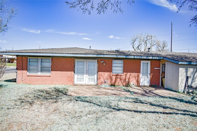 back of property with a lawn, a patio, fence, french doors, and brick siding