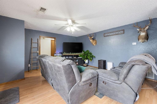 living room featuring visible vents, light wood-type flooring, and a ceiling fan