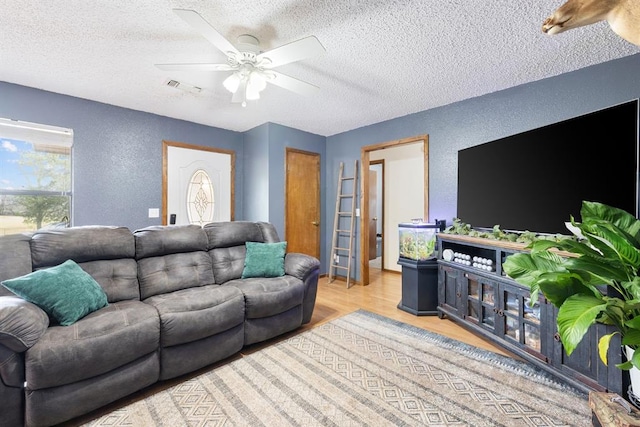 living room featuring wood finished floors, a textured wall, visible vents, and a textured ceiling