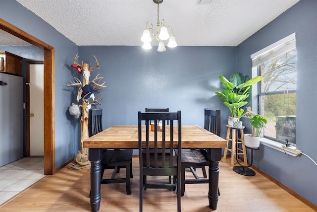 dining room with light wood finished floors, a chandelier, and a textured ceiling