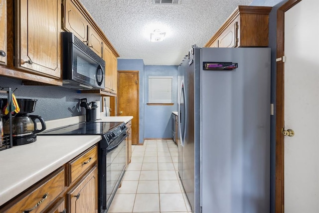 kitchen featuring light tile patterned floors, visible vents, black appliances, light countertops, and a textured ceiling