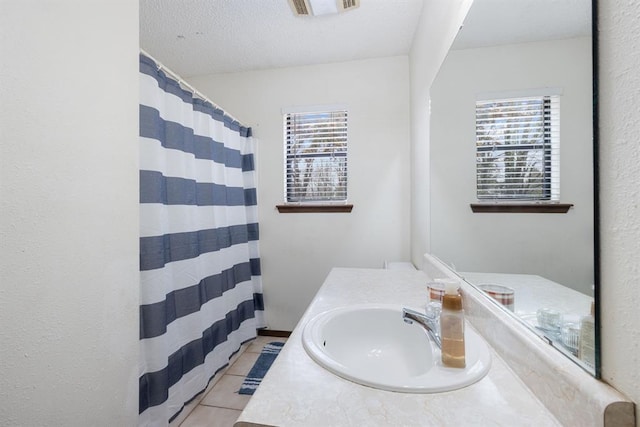 full bathroom with plenty of natural light, a textured ceiling, vanity, and tile patterned flooring