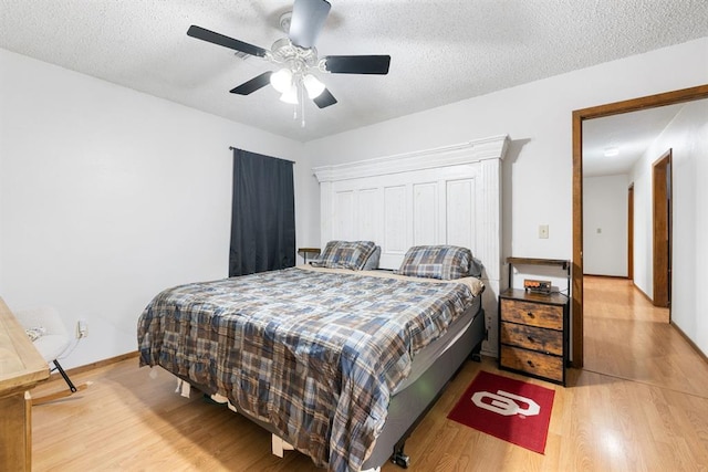 bedroom featuring ceiling fan, a textured ceiling, baseboards, and wood finished floors