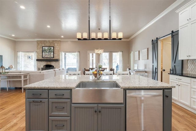 kitchen featuring a barn door, a notable chandelier, light wood-style flooring, and ornamental molding