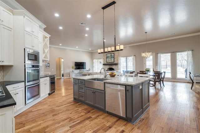 kitchen with visible vents, a sink, open floor plan, wine cooler, and appliances with stainless steel finishes