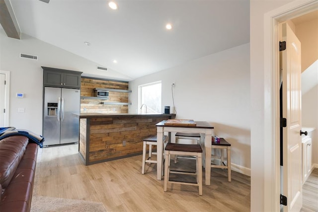 dining area featuring lofted ceiling, light wood-style floors, and visible vents