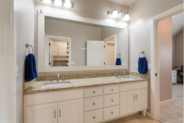 full bathroom featuring double vanity, baseboards, tile patterned floors, and a sink