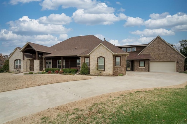 view of front of property with a garage, stone siding, brick siding, and driveway