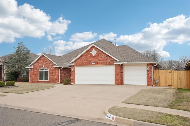 view of front of house with brick siding, concrete driveway, roof with shingles, an attached garage, and a gate