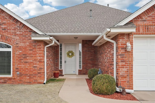 property entrance featuring brick siding, a shingled roof, and a garage