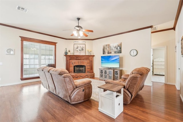 living room with visible vents, a brick fireplace, baseboards, and wood finished floors