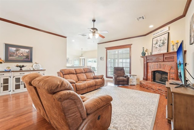 living room featuring visible vents, light wood-style floors, a brick fireplace, and ornamental molding