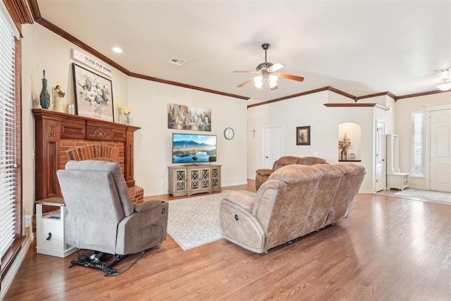 living room with arched walkways, visible vents, ornamental molding, and wood finished floors