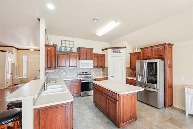 kitchen featuring a peninsula, stainless steel appliances, light countertops, and a sink