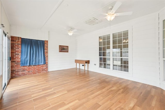 empty room featuring brick wall, a ceiling fan, and light wood finished floors