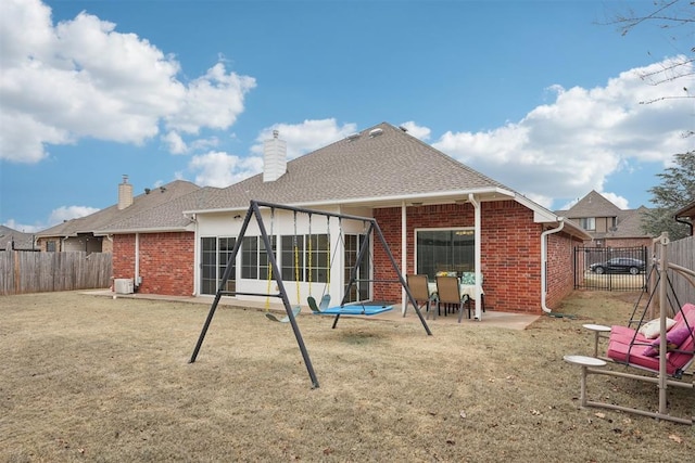 rear view of house featuring brick siding, a fenced backyard, and a patio