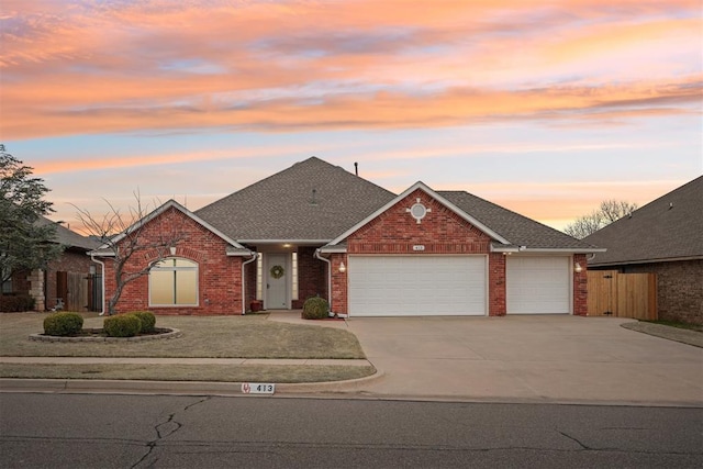 view of front of home featuring a garage, brick siding, concrete driveway, and fence