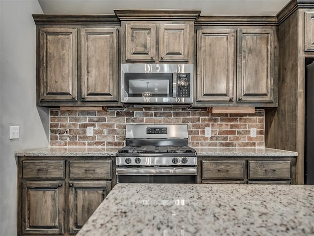 kitchen featuring tasteful backsplash, dark brown cabinets, appliances with stainless steel finishes, and light stone counters