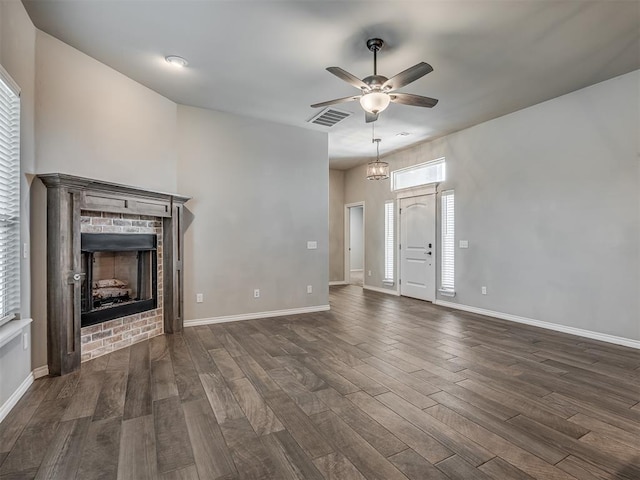 unfurnished living room with ceiling fan, visible vents, dark wood-style flooring, and a fireplace