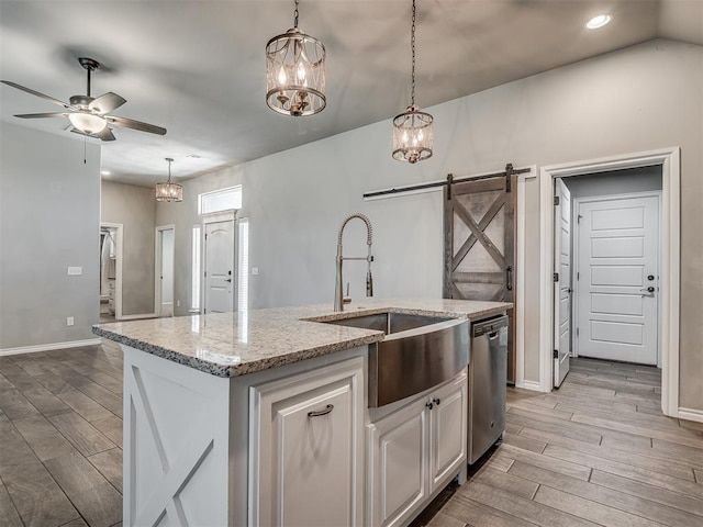 kitchen featuring wood finish floors, ceiling fan with notable chandelier, a sink, a barn door, and dishwasher