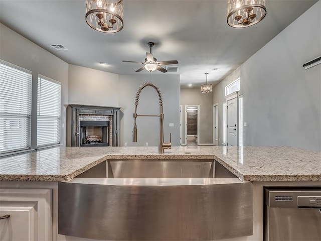 kitchen featuring a sink, visible vents, dishwasher, and a fireplace