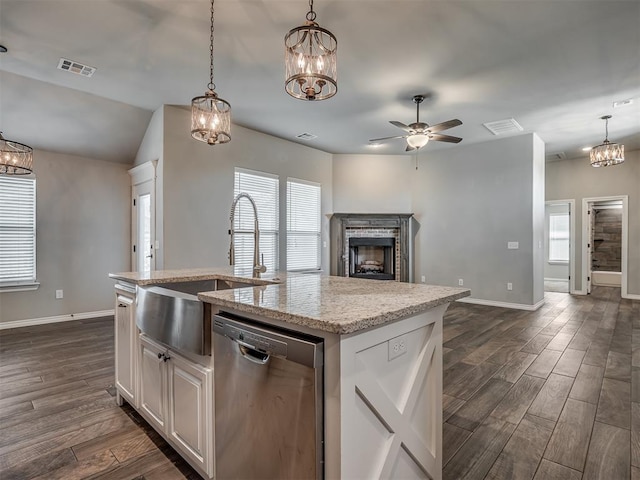 kitchen featuring visible vents, wood tiled floor, a fireplace, a sink, and stainless steel dishwasher