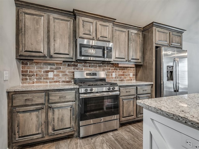 kitchen featuring wood finished floors, light stone countertops, and stainless steel appliances