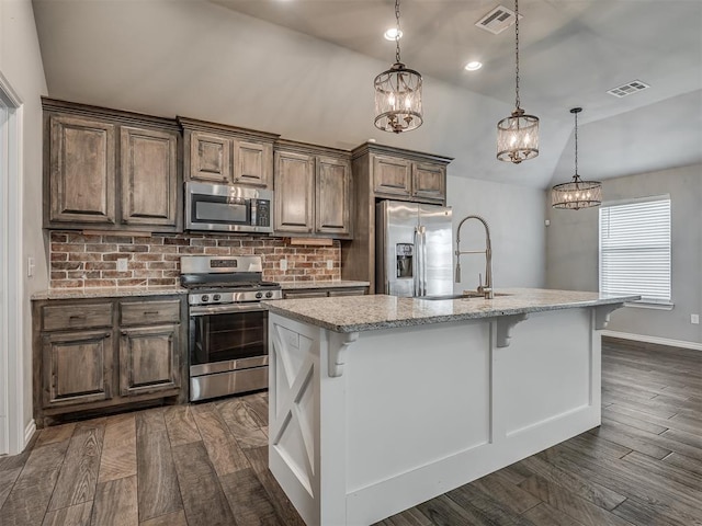 kitchen featuring a breakfast bar, a sink, backsplash, dark wood finished floors, and stainless steel appliances