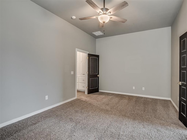 carpeted spare room with visible vents, baseboards, and a ceiling fan