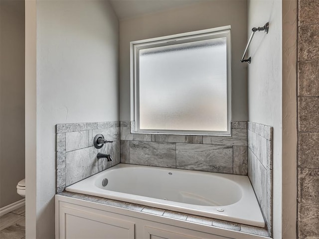 bathroom with a garden tub and toilet