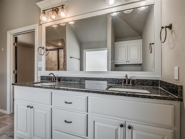 bathroom with double vanity, a tile shower, and a sink