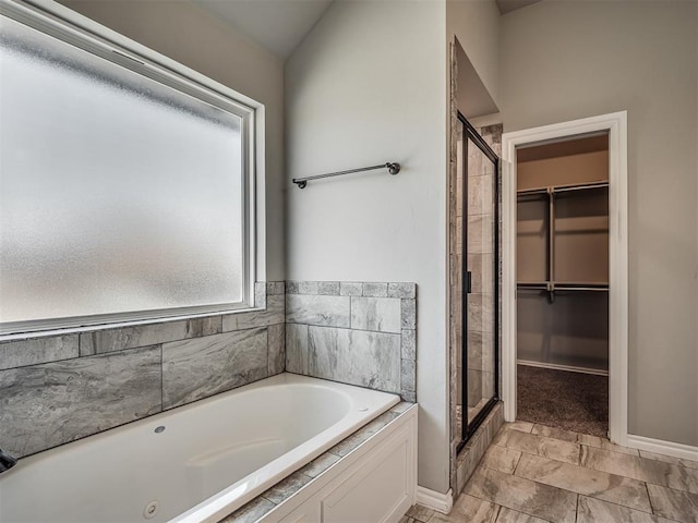 full bath with baseboards, a spacious closet, a bath, and a shower stall