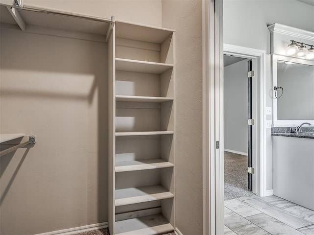 spacious closet with marble finish floor and a sink