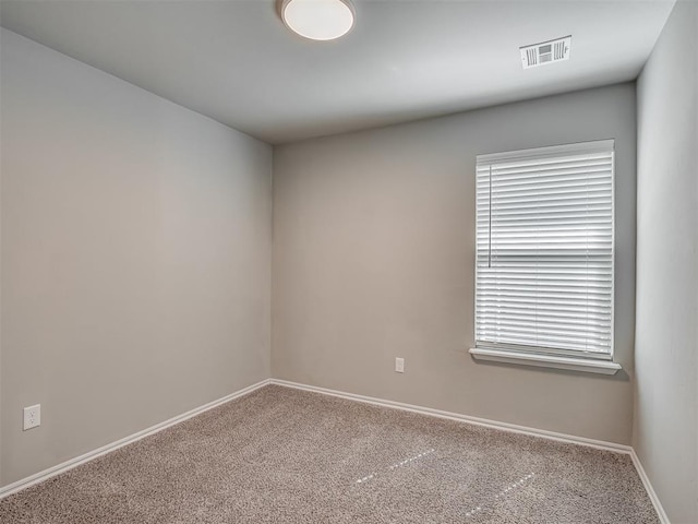 empty room with carpet, visible vents, and baseboards