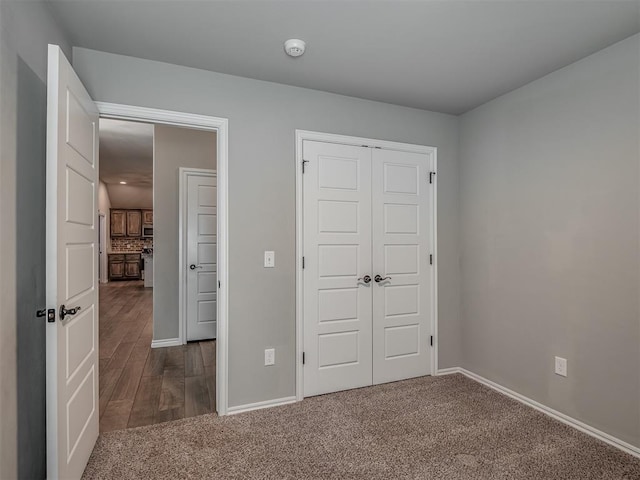 unfurnished bedroom featuring a closet, baseboards, and carpet flooring