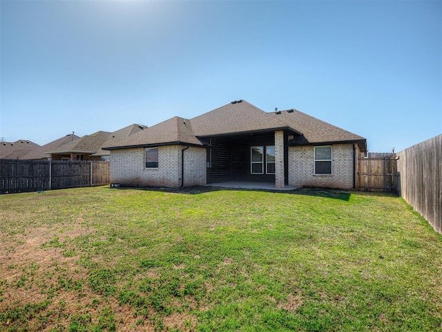 rear view of property with brick siding, a shingled roof, a fenced backyard, a yard, and a patio