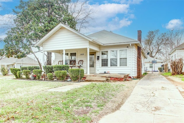 bungalow with a front lawn, a porch, and a chimney