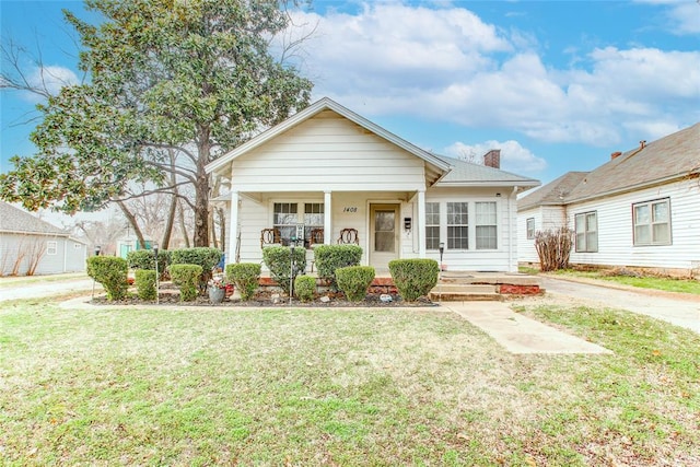 bungalow with a porch, a chimney, and a front lawn