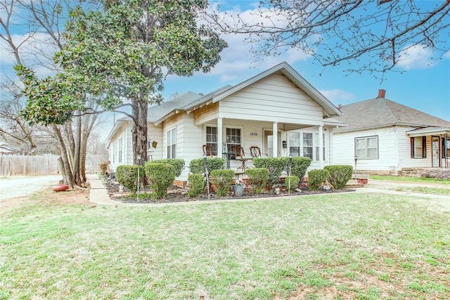 bungalow-style home with a front lawn, fence, and covered porch