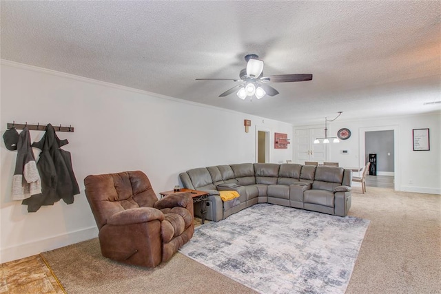 living room featuring light colored carpet, a textured ceiling, ceiling fan, and ornamental molding