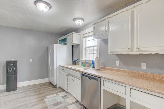 kitchen with dishwasher, a textured ceiling, freestanding refrigerator, and a sink