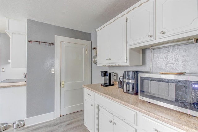 kitchen with stainless steel microwave, white cabinets, and light countertops