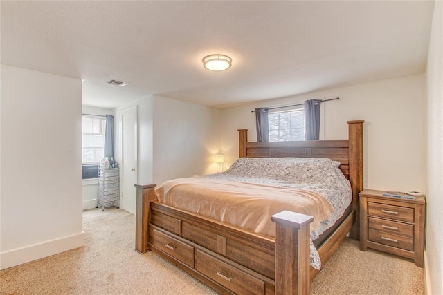 bedroom with multiple windows, baseboards, visible vents, and light carpet