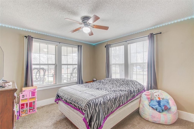 carpeted bedroom featuring multiple windows, baseboards, and a textured ceiling